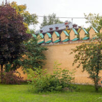 Часть стены монастыря женского двора Преображенского монастыря, на втором плане часть кровли больницы архитектора Льва Кекушева (лето, 2019 г.)